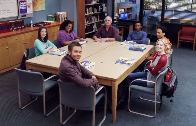 Seven students sit around a study table in a library. The students portrayed are the main characters in the television show Community.