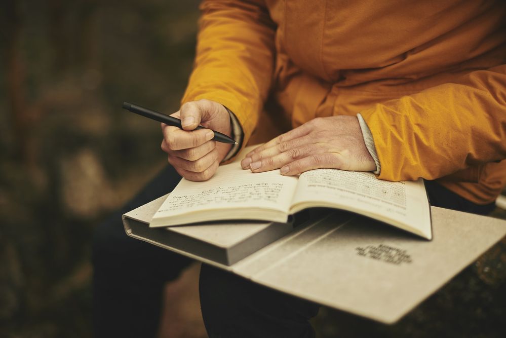 A person writing in a notebook with a pen