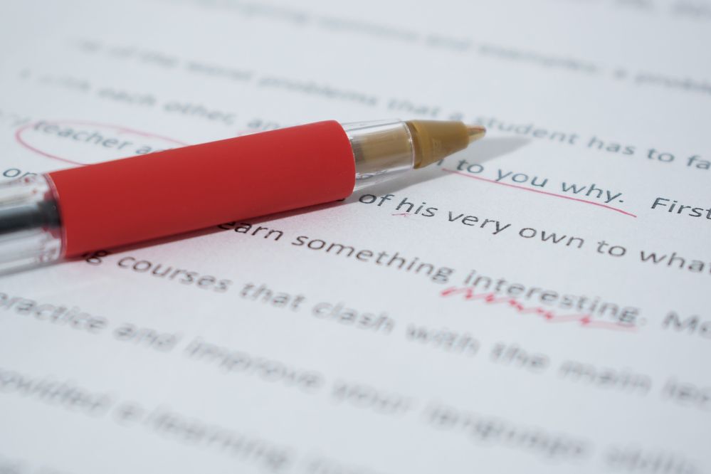 red pen and essay, essay with edits, copyediting, proofreading