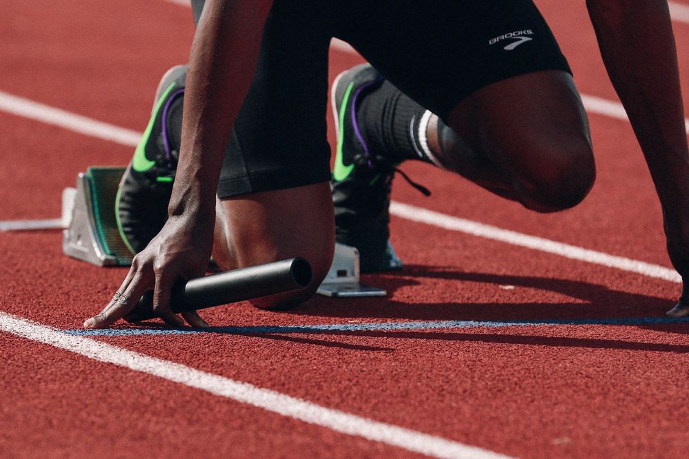 A runner, holding a baton, at the starting line on a track