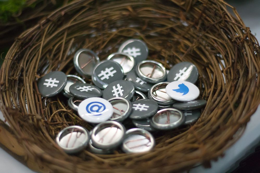 Close-up photograph of a bird’s nest with Twitter-branded button pins inside.jpg
