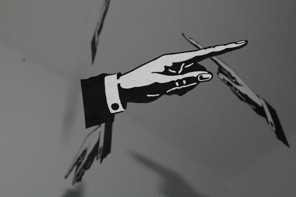 Black and white photograph of a mobile with cut-out images of cartoon hands pointing fingers in different directions.jpg