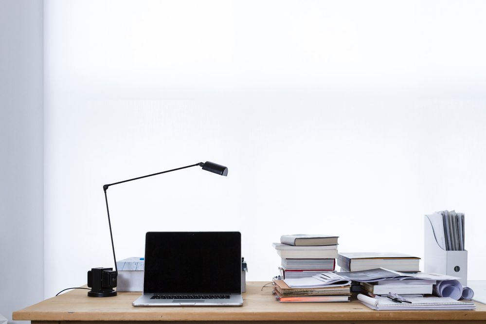 A desk with a lamp, laptop, and books on top of it. Photo by freddie marriage on Unsplash.