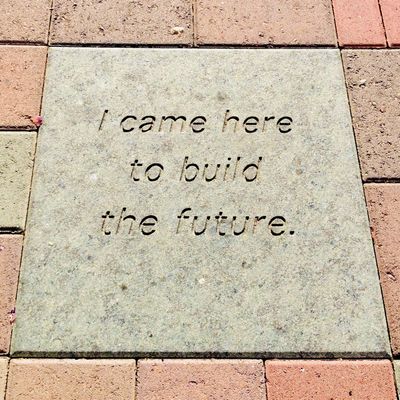 I came here to build the future. Inscription on a rectangular light-colored stone surrounded by red flagstones..jpg