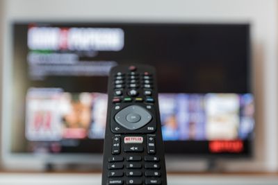 Black TV remote pointing at a TV in the background.jpg