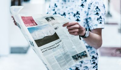 Person reading politics section of newspaper with headline related to climate change.jpg