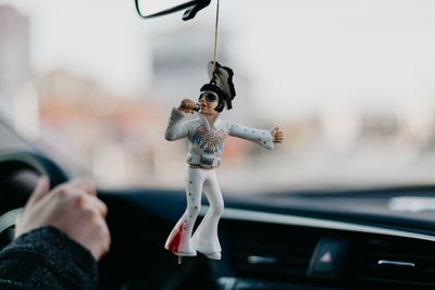 An Elvis figurine dangles from a car's rearview mirror.jpg