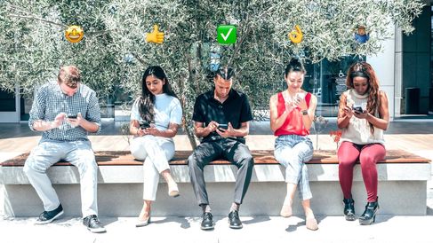 people looking at smartphones with various emojis floating above their heads.jpg