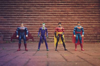 Four DC Comics action figures lined up against brick wall background.jpg