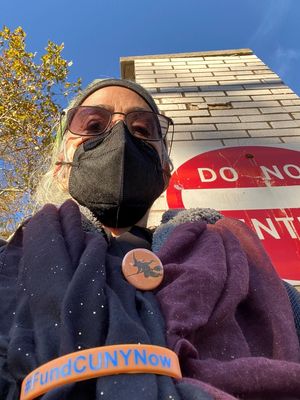 Halloween selfie by the campus gate in front of a Do Not Enter sign posted on a white brick wall. One of the bricks above the sign has noticeably deteriorated. Photo by Susan Bernstein, October 31, 2023